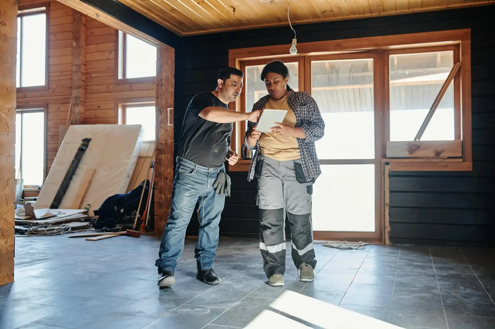 split scene showing custom home concept sketches on one side and a builder reviewing digital construction plans on a tablet at an active jobsite on the other