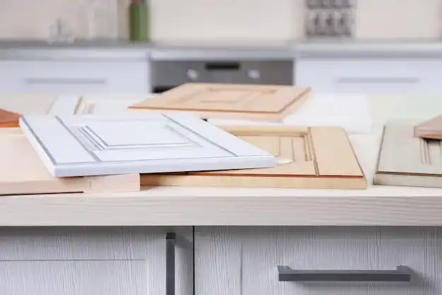 Seattle homeowner reviewing renovation plans at a dining table with contractor samples of paint, flooring, and quartz countertops, rainy neighborhood visible through window
