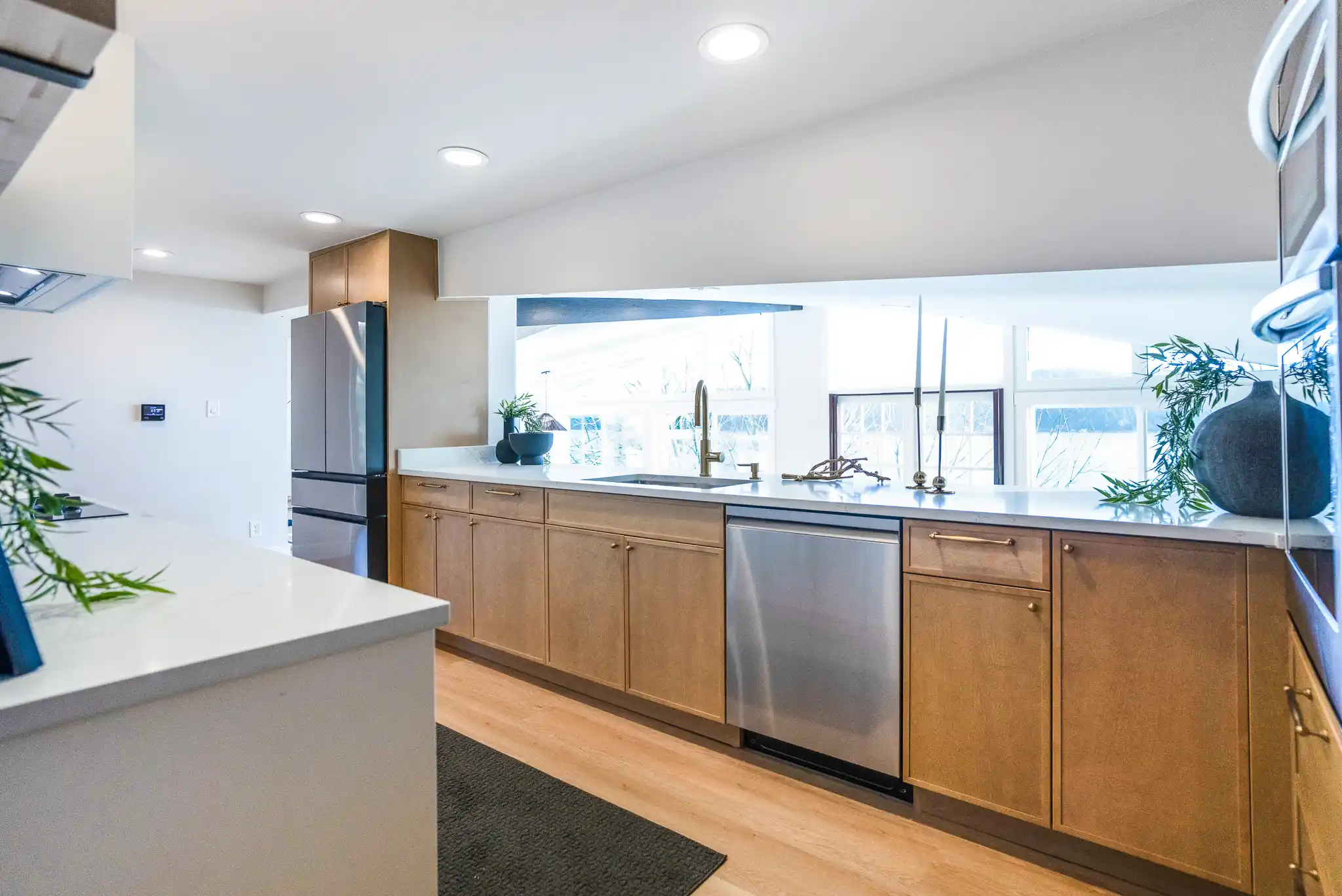 updated Seattle kitchen with matte navy cabinets, white quartz counters, brass hardware, oak shelves, and soft natural light from oversized windows