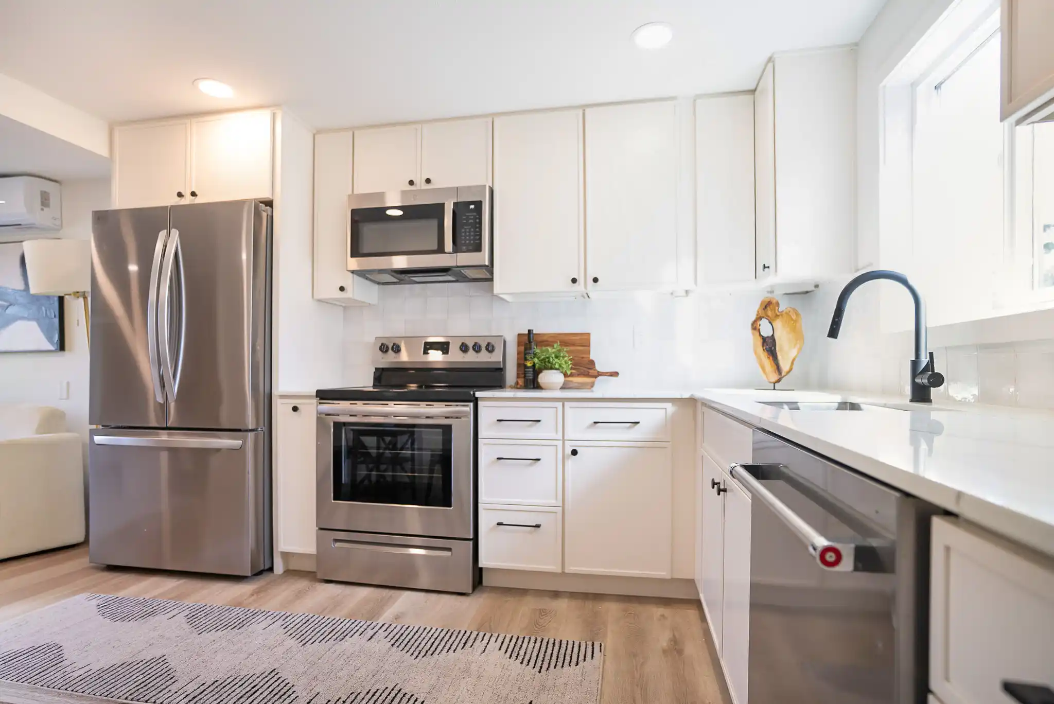 bright transitional kitchen remodel with shaker cabinets, quartz countertops, matte black hardware, large island, and warm oak flooring in a suburban Pacific Northwest home