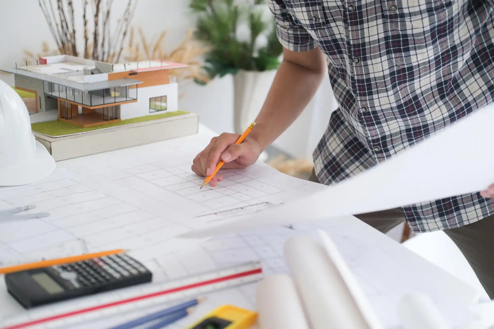 interior designer and custom home builder reviewing marble samples, brass hardware, and architectural plans on a large oak table in a bright design studio