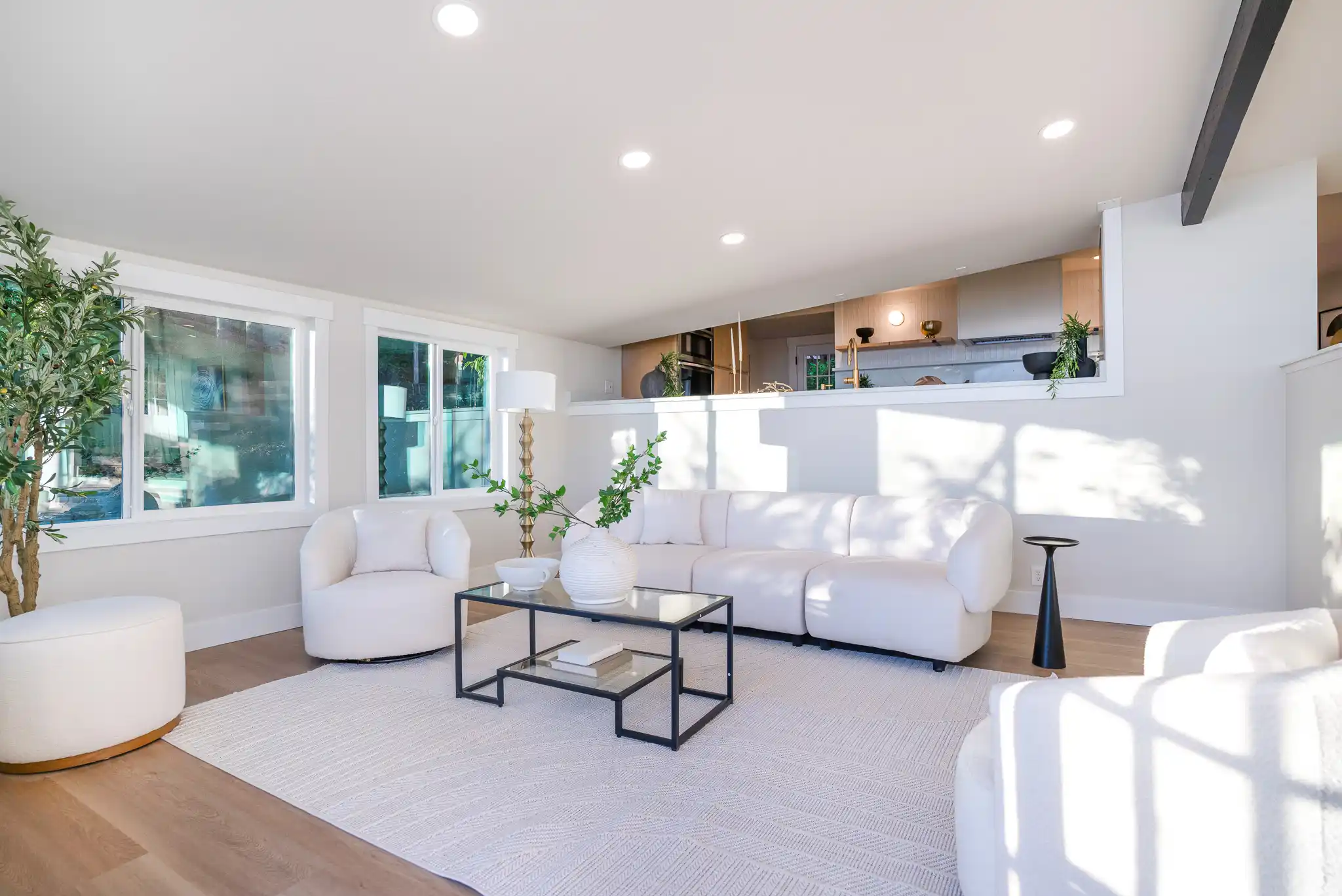 staged Seattle craftsman living room with freshly painted walls, refinished hardwood floors, natural light, and views of evergreen trees through large windows