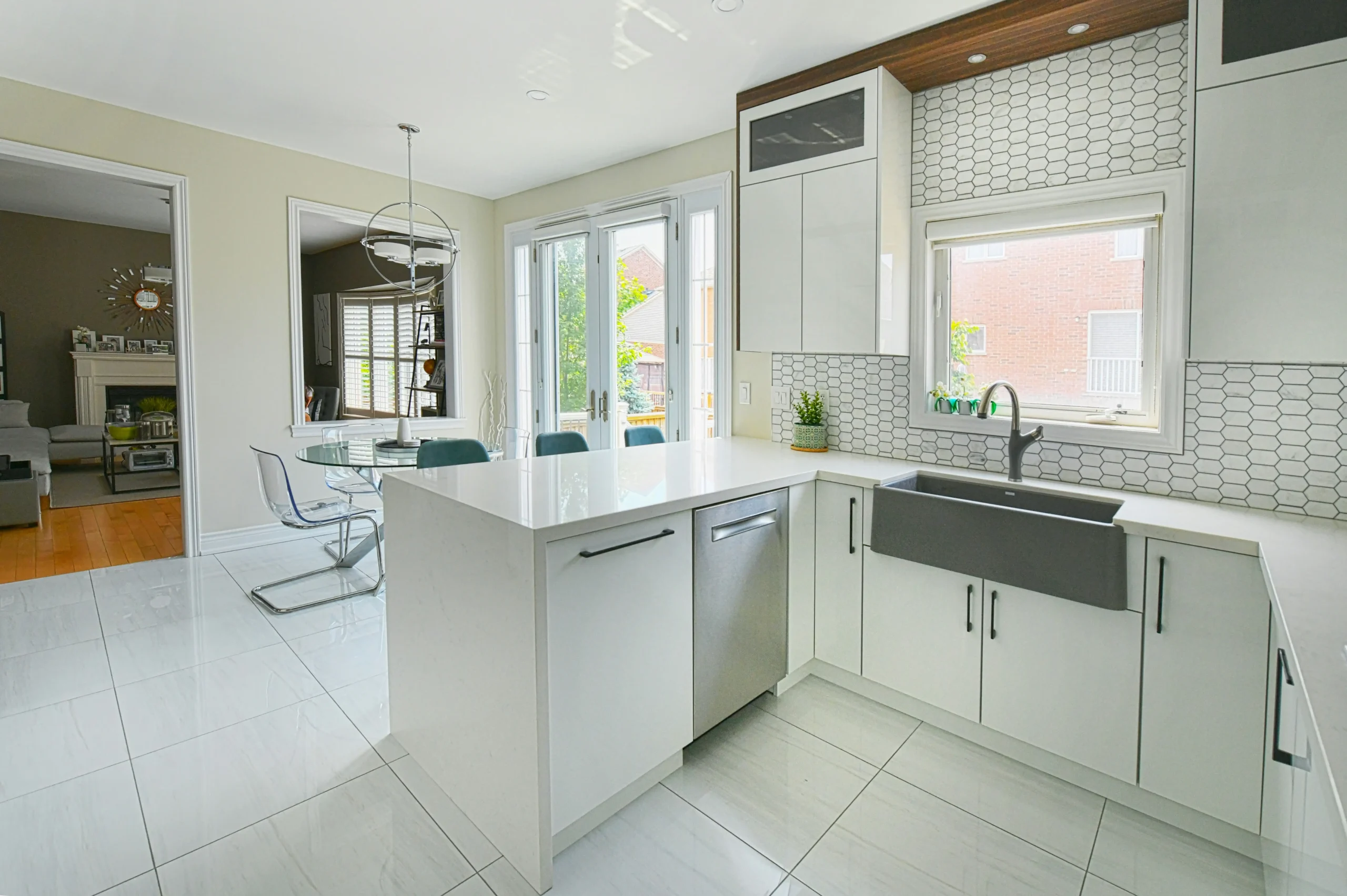 high-end custom kitchen with rift-cut white oak cabinets, waterfall quartz island, matte black fixtures, and full-height slab backsplash in warm natural light