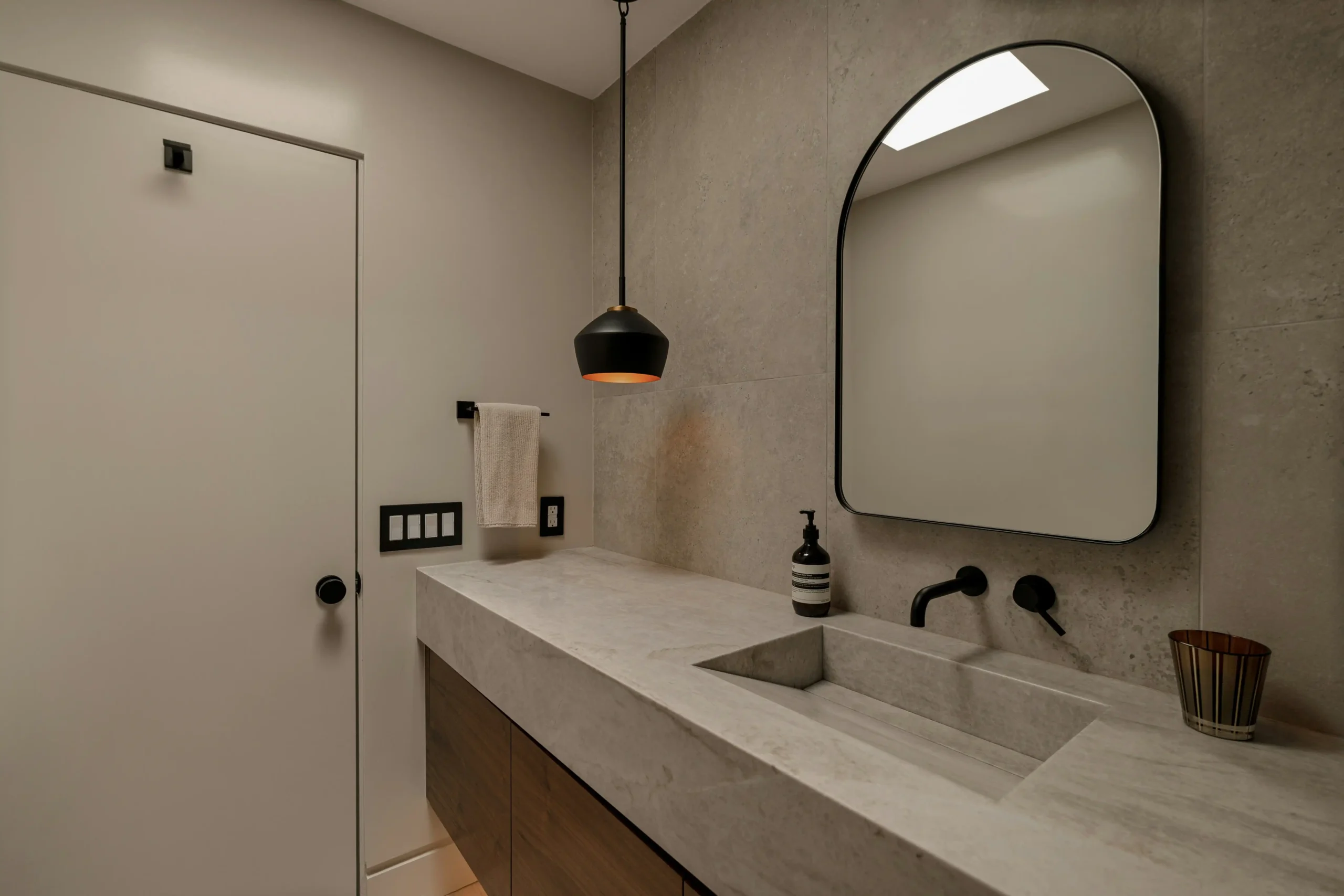 bright contemporary bathroom with soft gray painted walls, white vanity, black fixtures, steamy mirror, and natural window light showing moisture-resistant finishes
