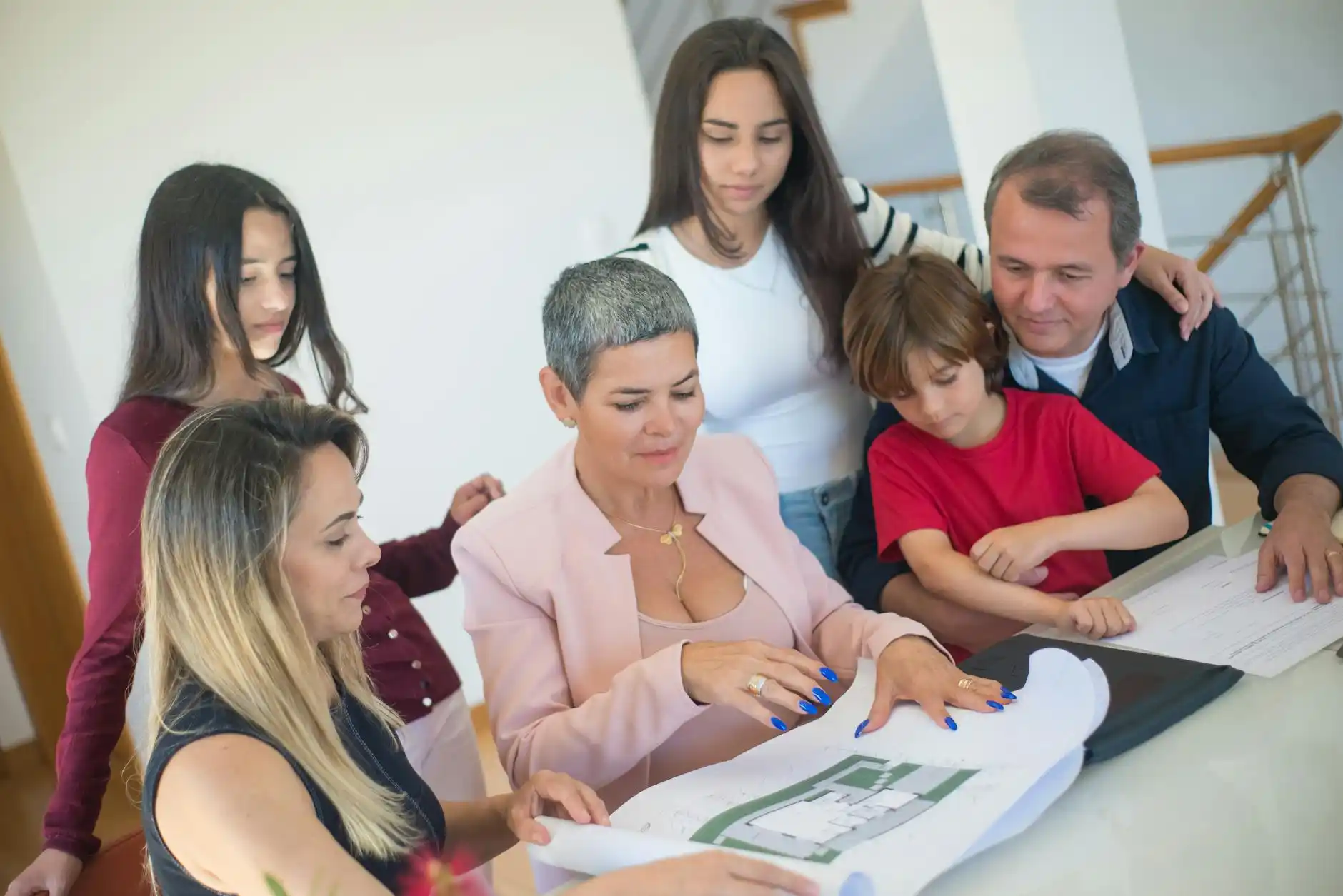 side-by-side scene of a fully customized luxury home blueprint meeting and a large suburban production home development with model homes and sales flags