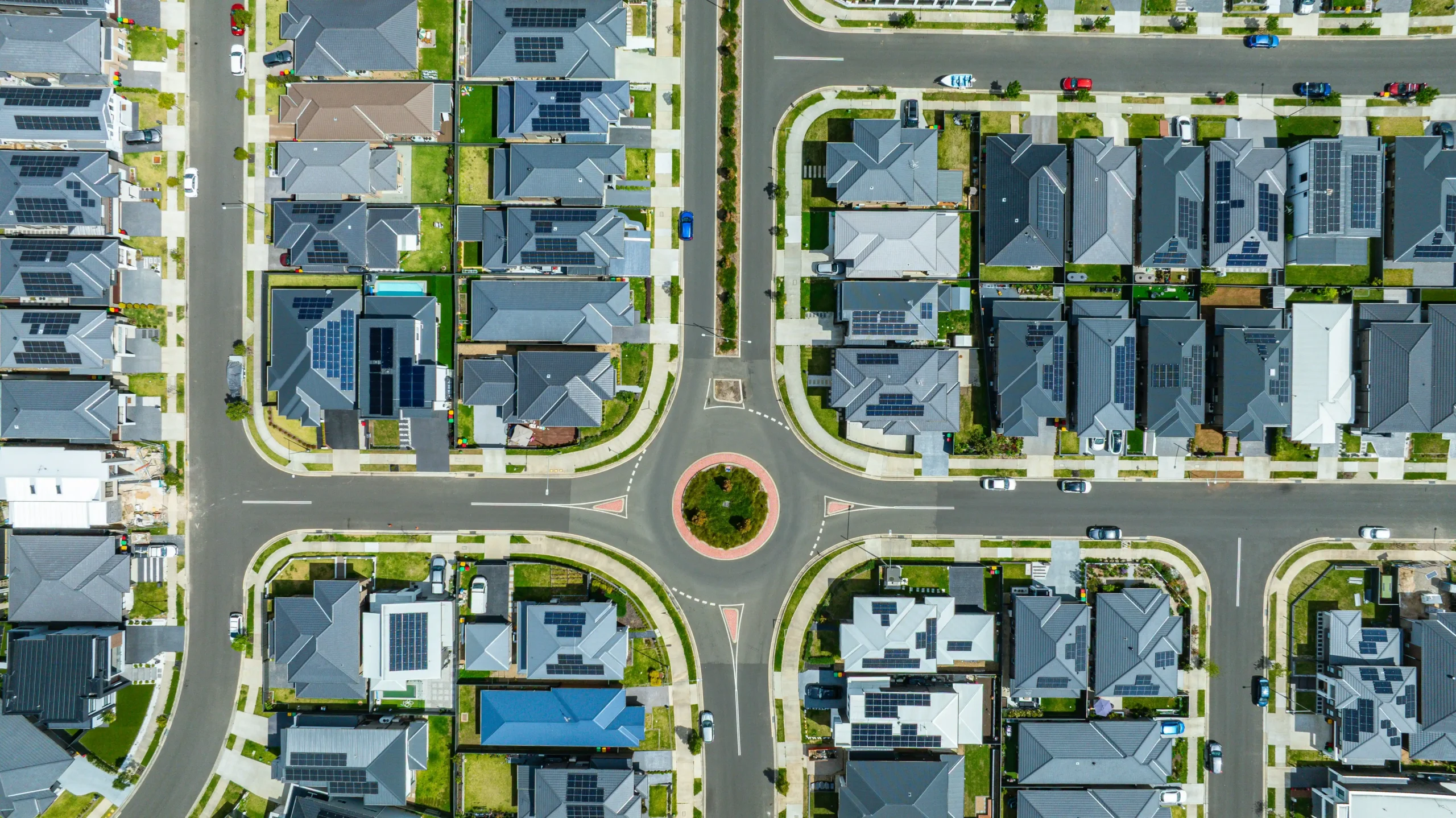 aerial view of a wooded private homesite overlooking a hillside contrasted with a neatly planned suburban subdivision of newly built homes and curved streets