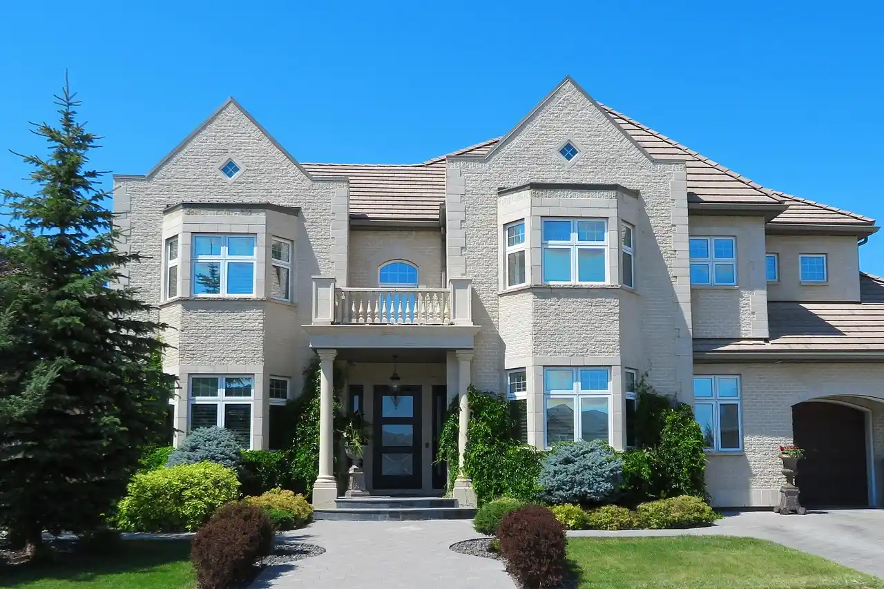 upscale craftsman custom home exterior with fiber cement siding, stone veneer columns, black framed windows, warm wood front door, and landscaped front walkway at golden hour