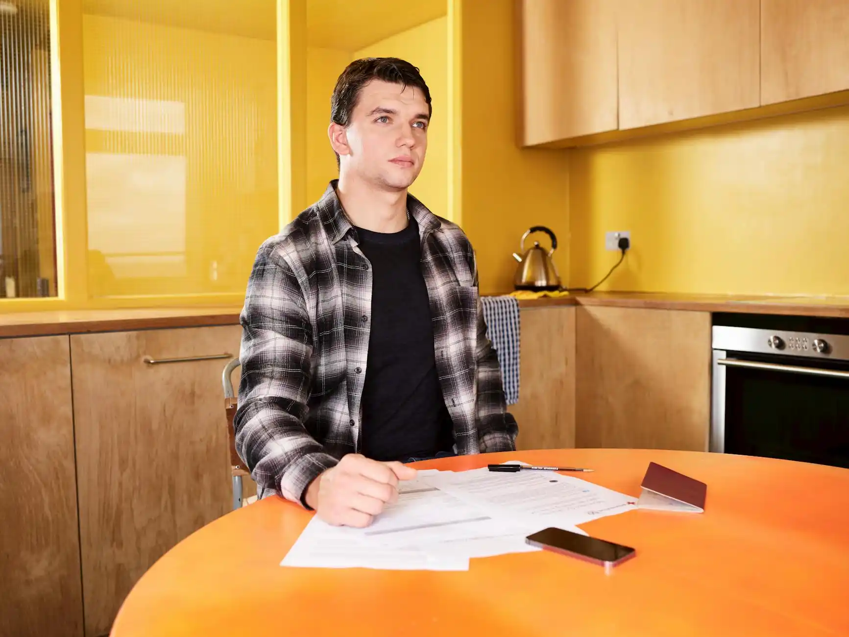 Seattle-area home seller reviewing renovation paperwork at a dining table with contractor estimate sheets, property photos, and a laptop showing closing documents