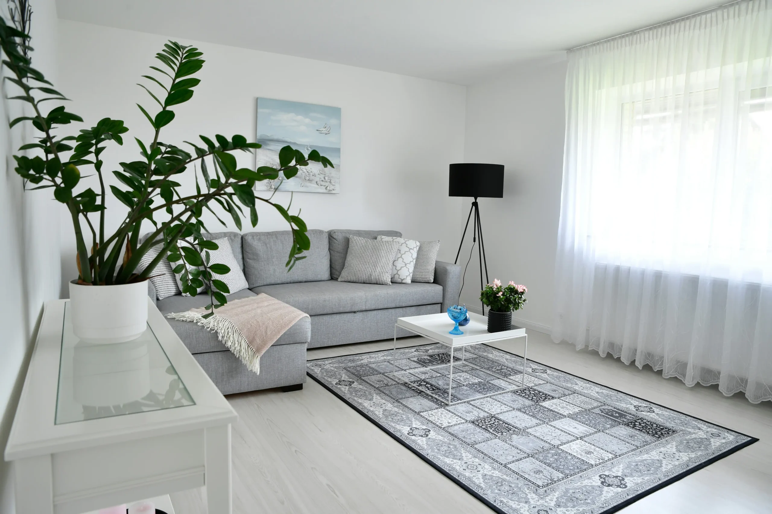 staged Seattle living room in a renovated craftsman home with light oak floors, soft gray walls, large windows, and a realtor reviewing renovation plans with homeowners
