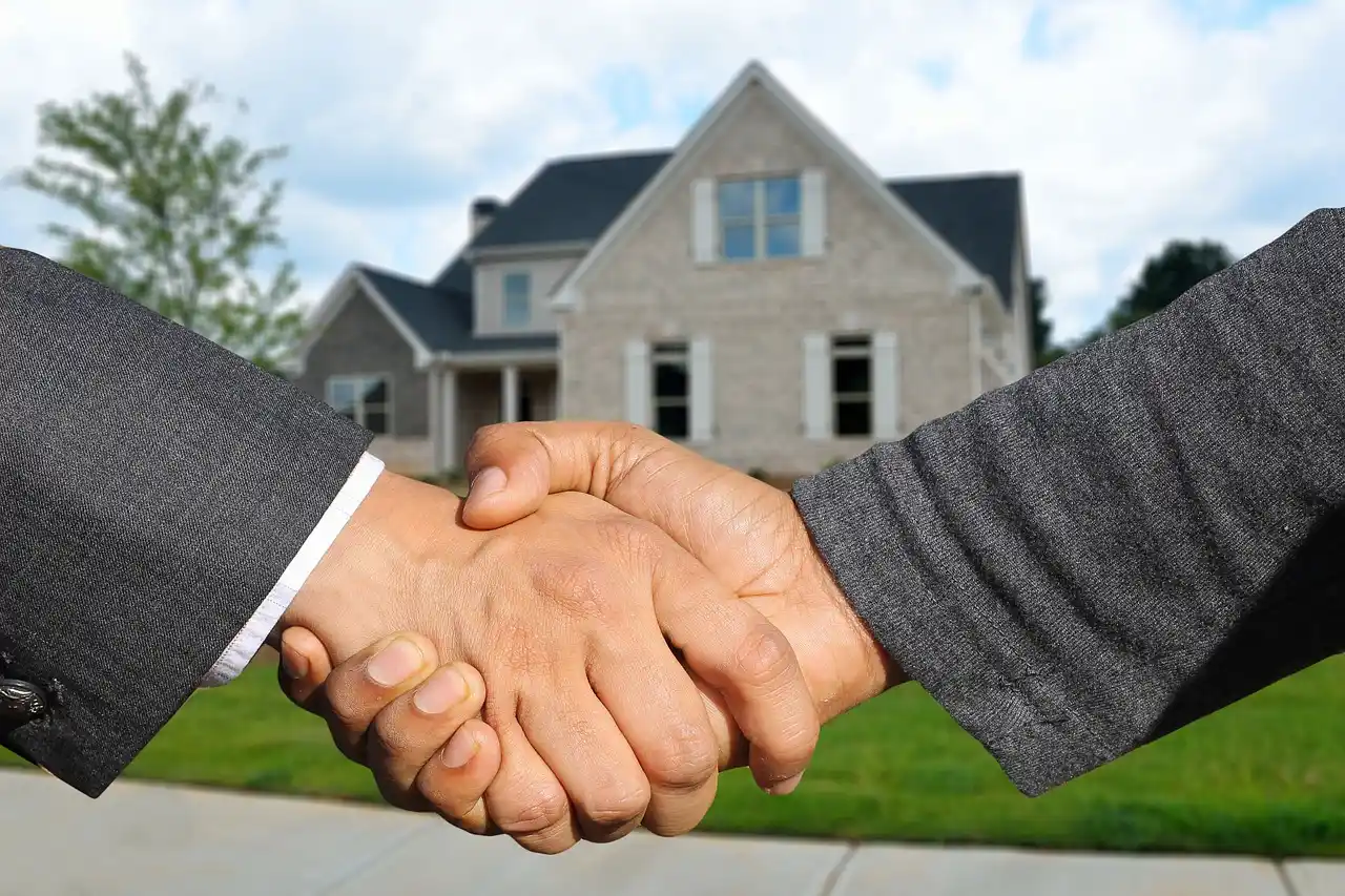 real estate agent, contractor, and homeowners standing in a bright remodeled Seattle kitchen discussing listing strategy with a laptop and printed home comps