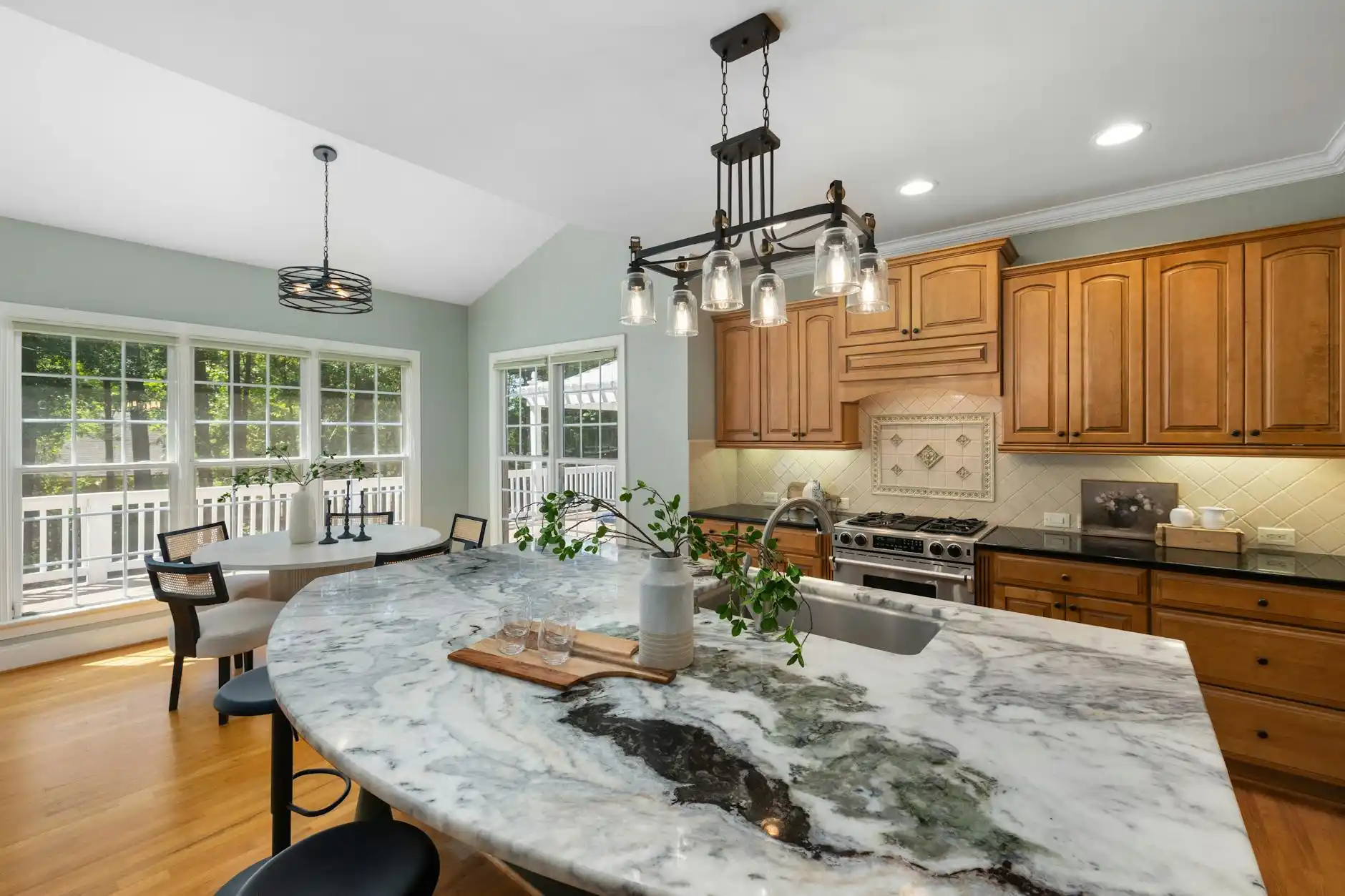 bright transitional kitchen under renovation with half-installed shaker cabinets, stacked tile backsplash, quartz countertops covered for protection, and tools neatly arranged o...