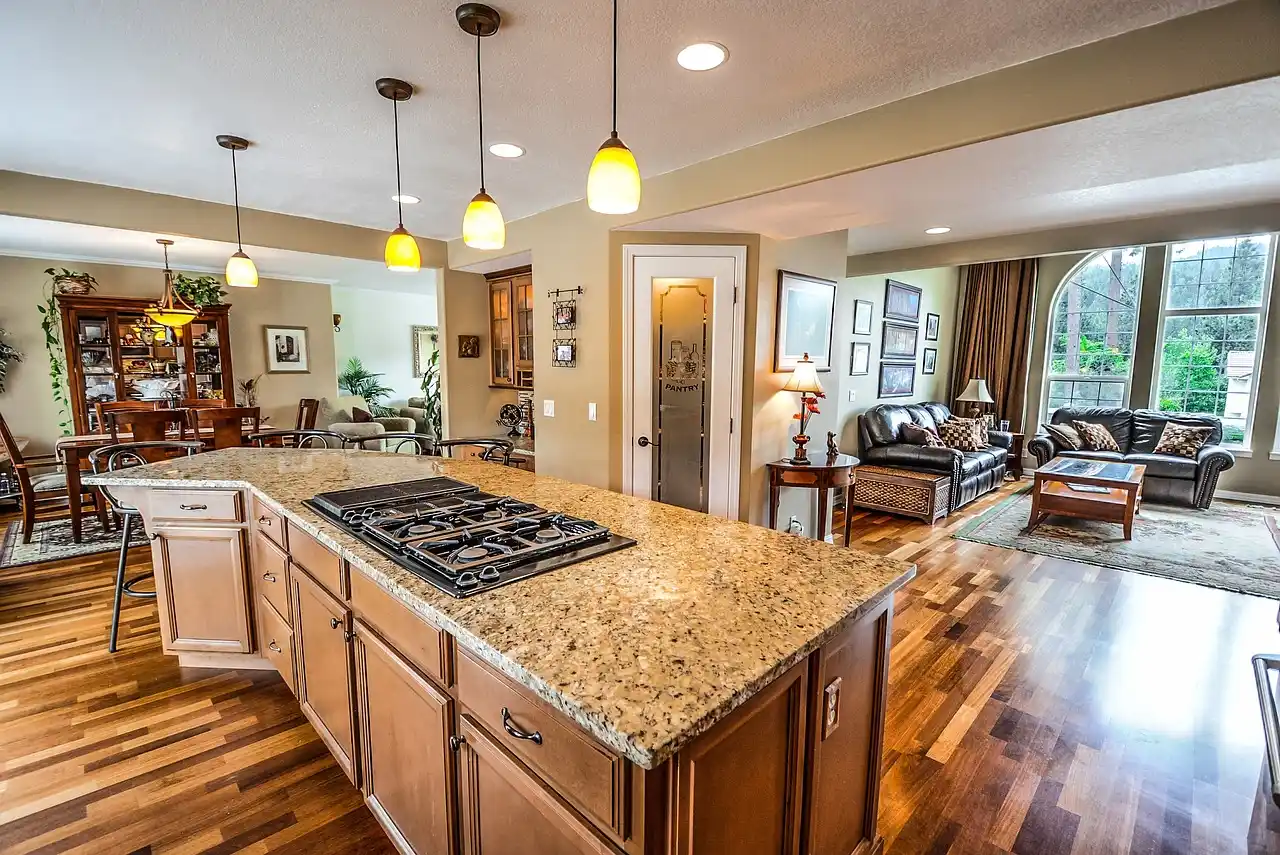 upscale custom home interior with unfinished white oak cabinets, stacked stone fireplace, designer pendant lights, and workers reviewing finish samples