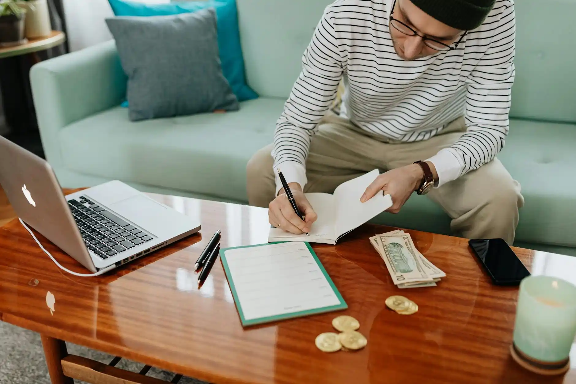 overhead view of a homeowner planning a kitchen renovation budget with paint swatches, cabinet samples, calculator, and handwritten cost list on a wooden table