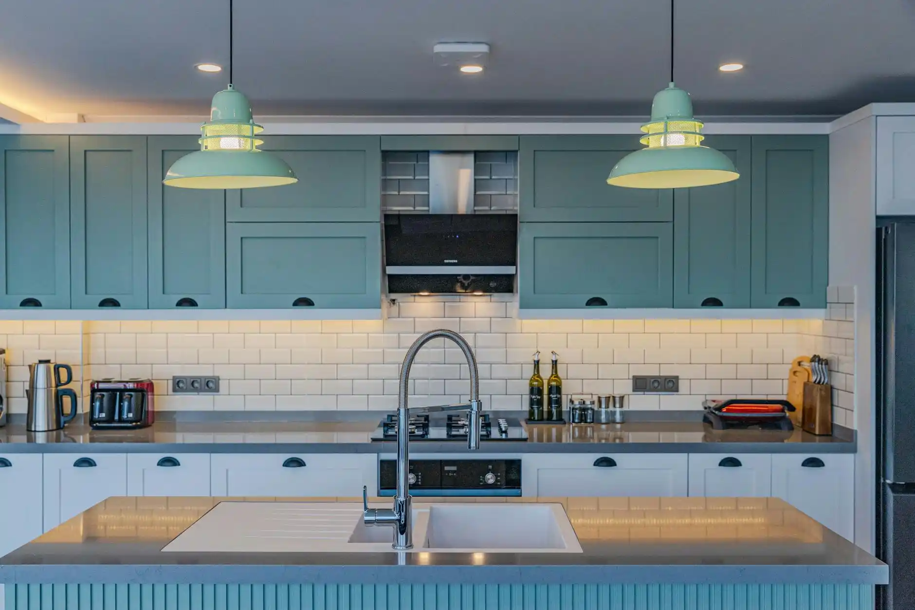 bright transitional kitchen featuring painted sage green cabinets, white subway tile backsplash, butcher block island, and luxury vinyl plank flooring