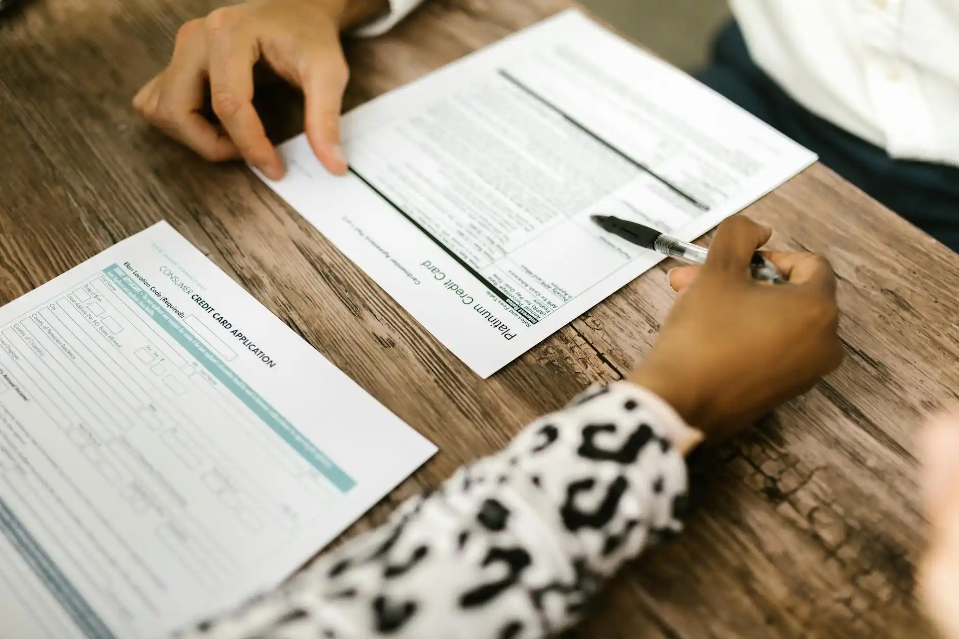 Seattle-area homeowner reviewing renovation loan paperwork at a dining table with contractor bids, calculator, and house plans spread out in natural morning light