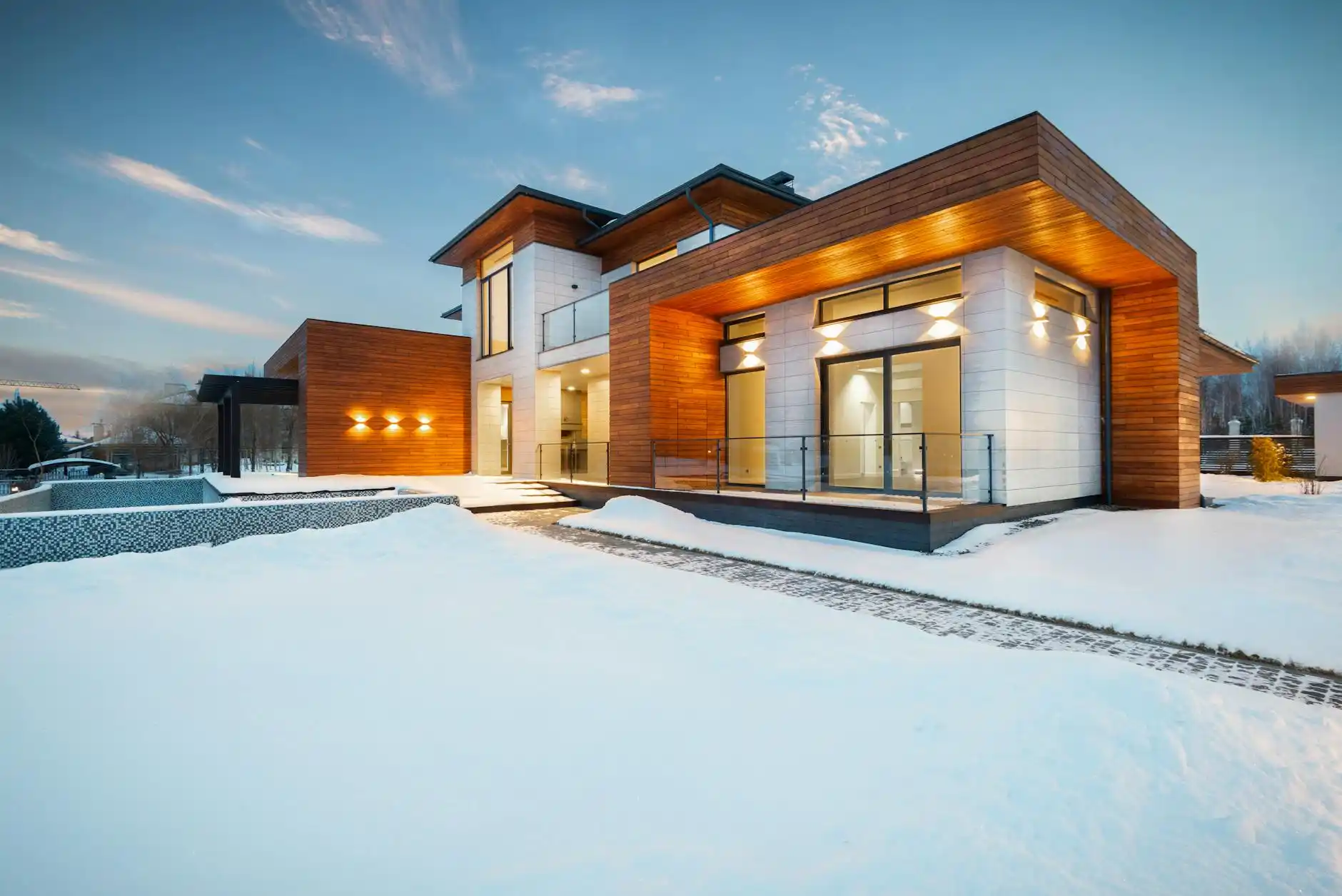 luxury custom home exterior at golden hour with stone façade, black-framed windows, manicured landscaping, and a builder reviewing warranty documents with homeowners on the fron...