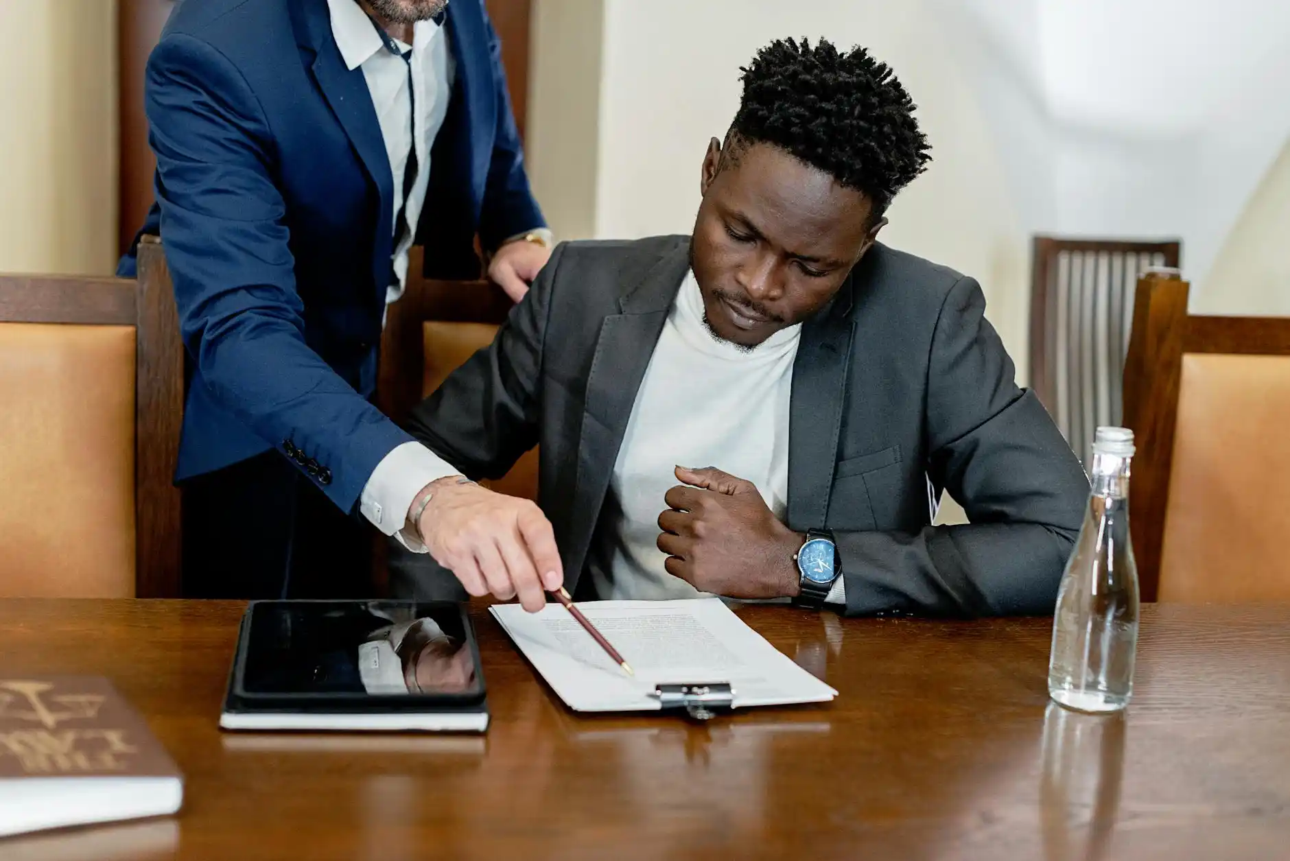 homeowner and project manager seated at a dining table in a newly finished custom home, reviewing a tablet with service request timeline and repair checklist
