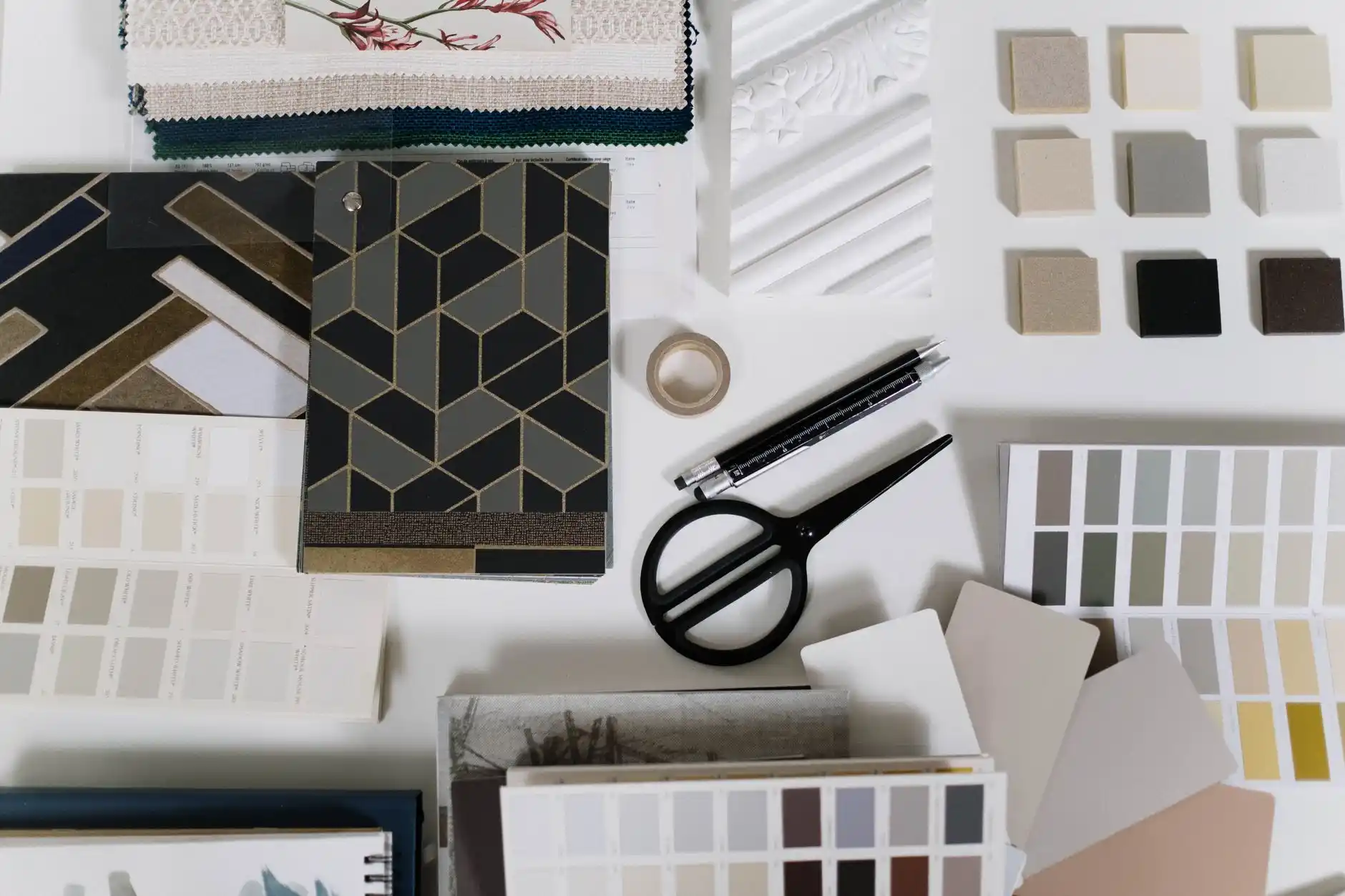 upscale kitchen material selection board with quartz slab sample, matte black faucet, white oak cabinet door, contract allowance worksheet, and calculator under natural daylight