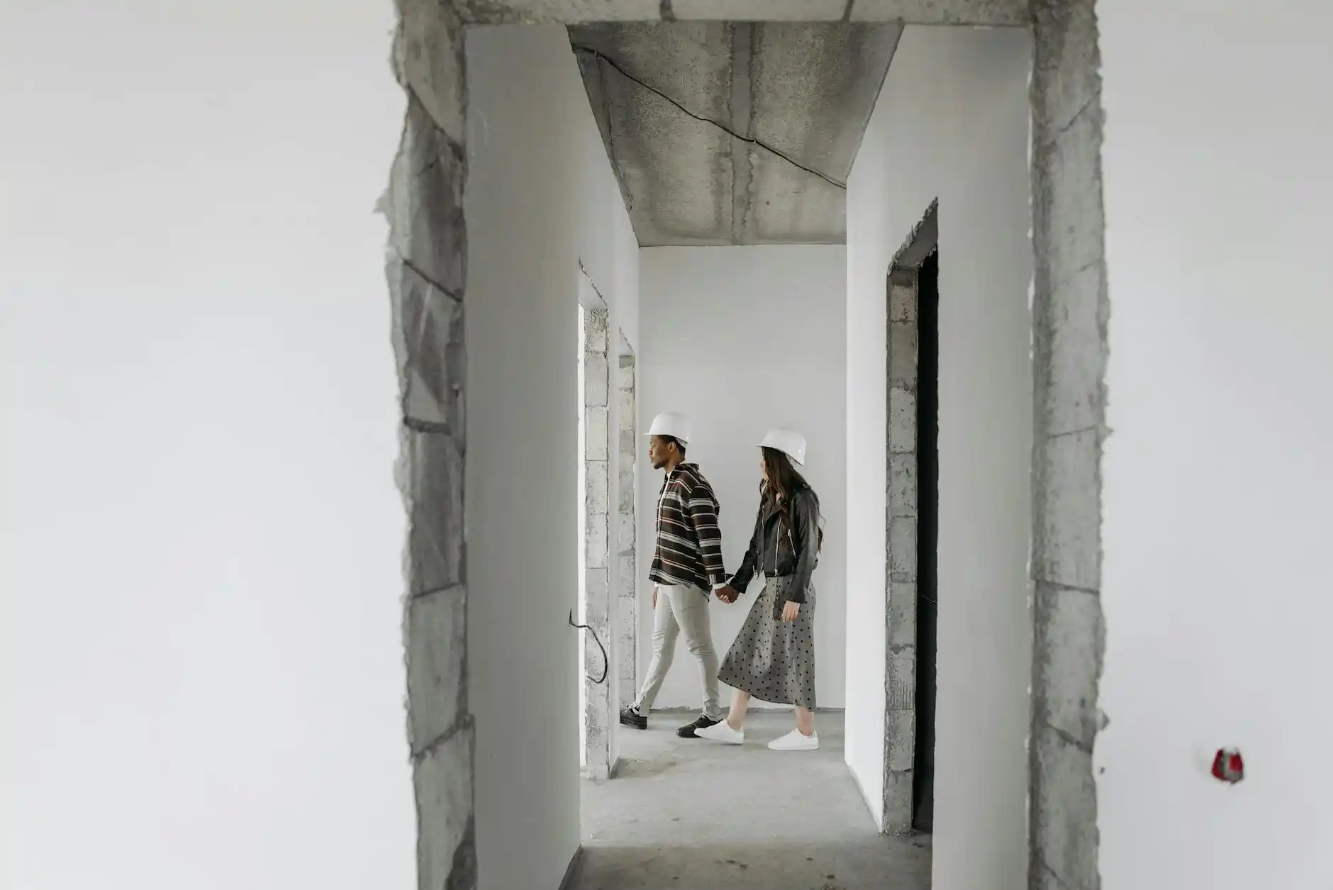 homeowners and builder wearing hard hats during a framed custom home walkthrough, sunlight coming through large picture windows, with mountain views and visible room layout markers