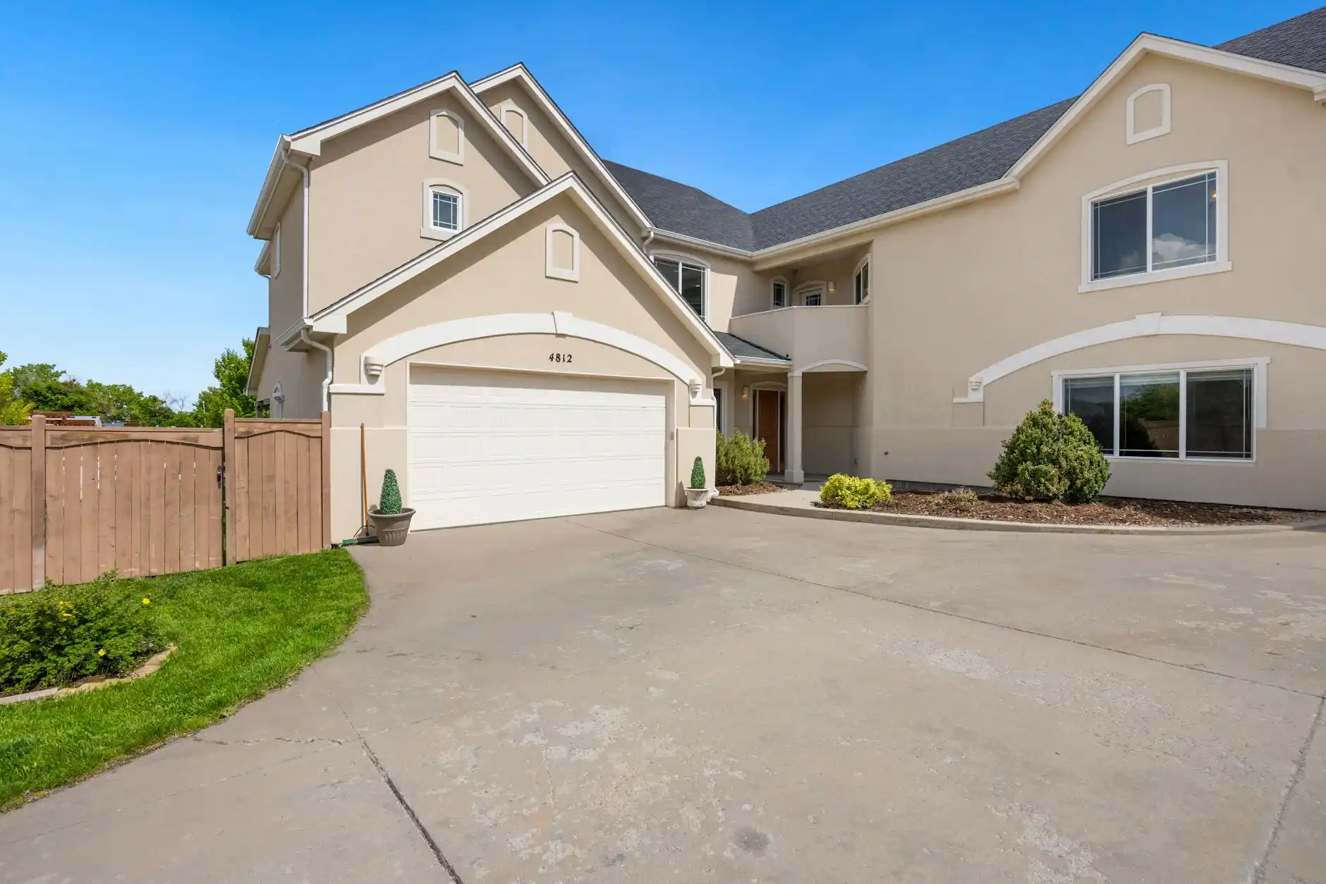elegant finished custom home entryway with black steel front door, warm wood floors, statement chandelier, and homeowners smiling with builder during final handoff