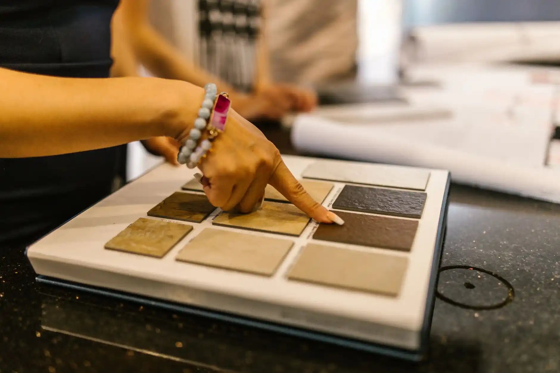 designer and homeowner selecting premium stone slabs, cabinetry finishes, and brushed brass fixtures in a bright materials showroom for a custom home