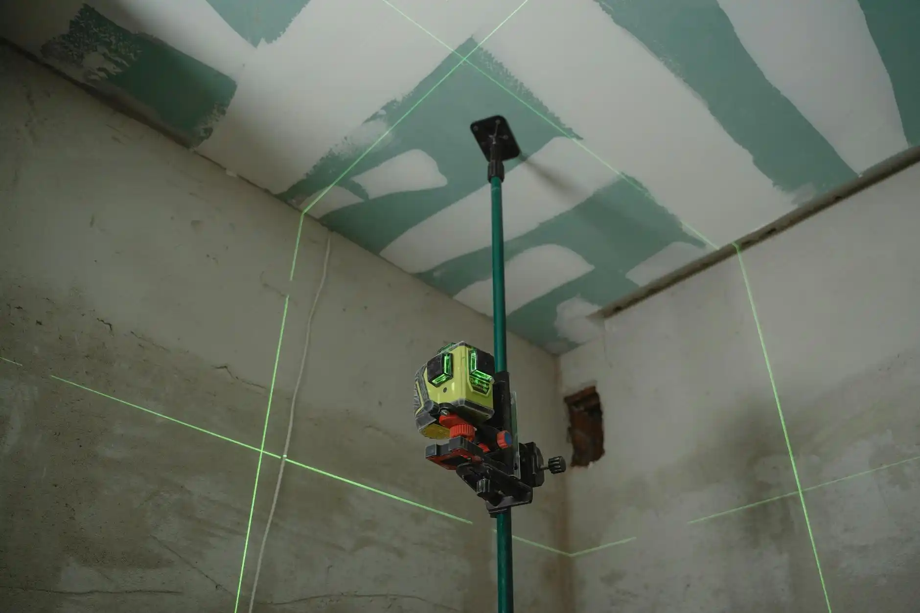 hillside residential lot with survey stakes, laser level equipment, and a builder pointing out grading plans under a bright blue sky