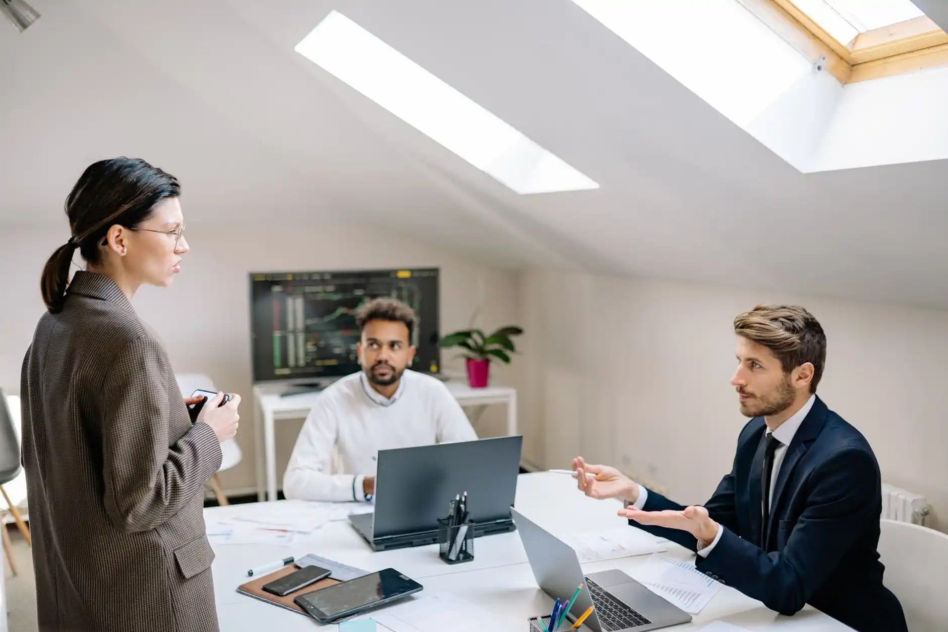 professional meeting in a bright lending office with a couple reviewing builder contracts, site plans, and a pre-approval checklist with a loan officer