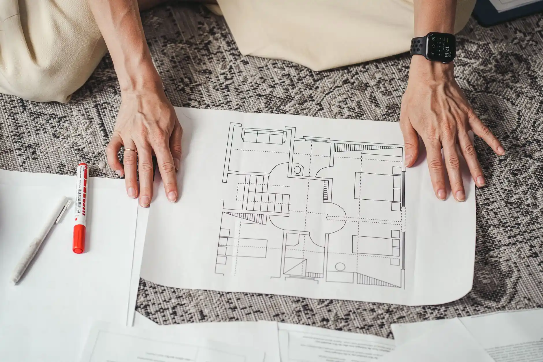 architect and homeowner reviewing detailed floor plans on a large monitor beside kitchen cabinet samples, hardwood planks, and stone countertops