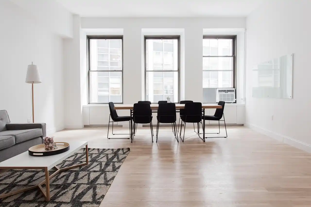 happy homeowners walking through a finished custom living room with vaulted ceilings, wide oak floors, built-in fireplace, and floor-to-ceiling windows