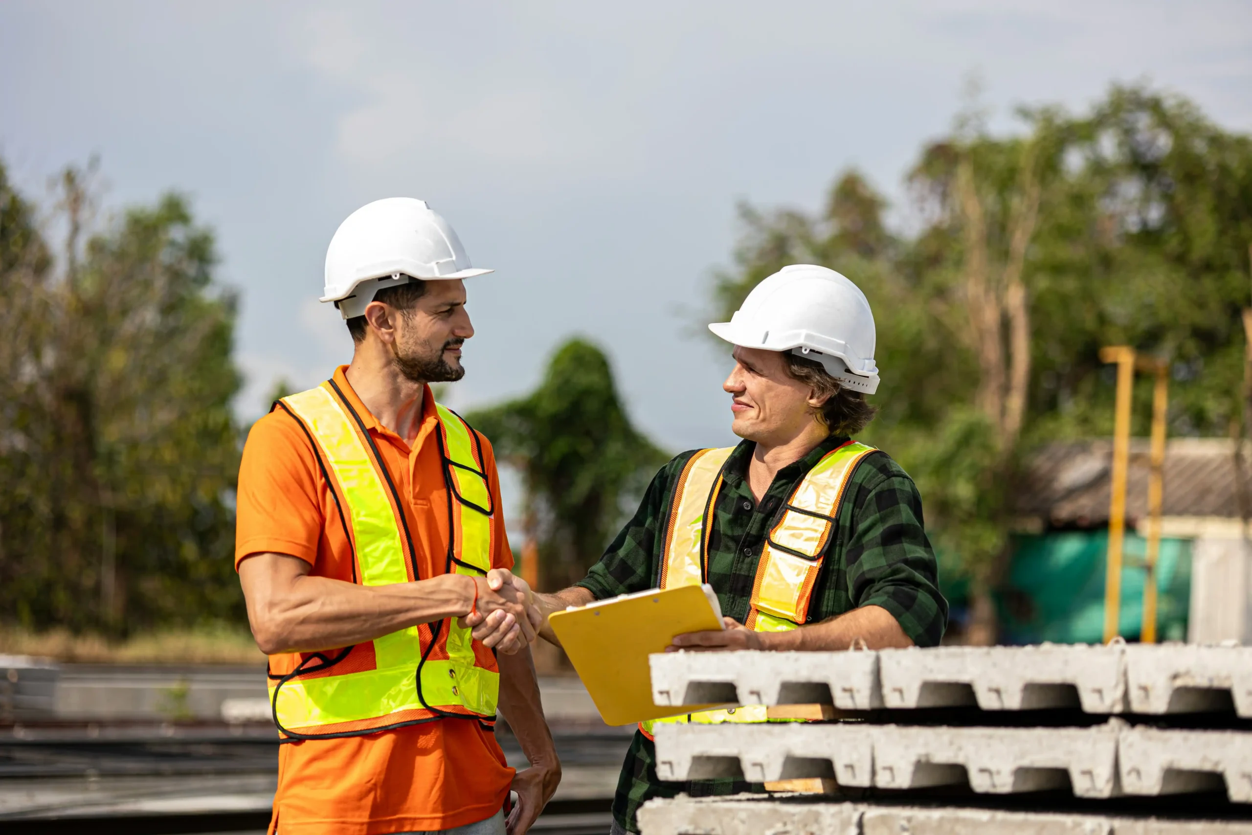 Homeowner and residential contractor reviewing ADU floor plans and an itemized construction estimate at a kitchen table, with permit drawings and material samples visible