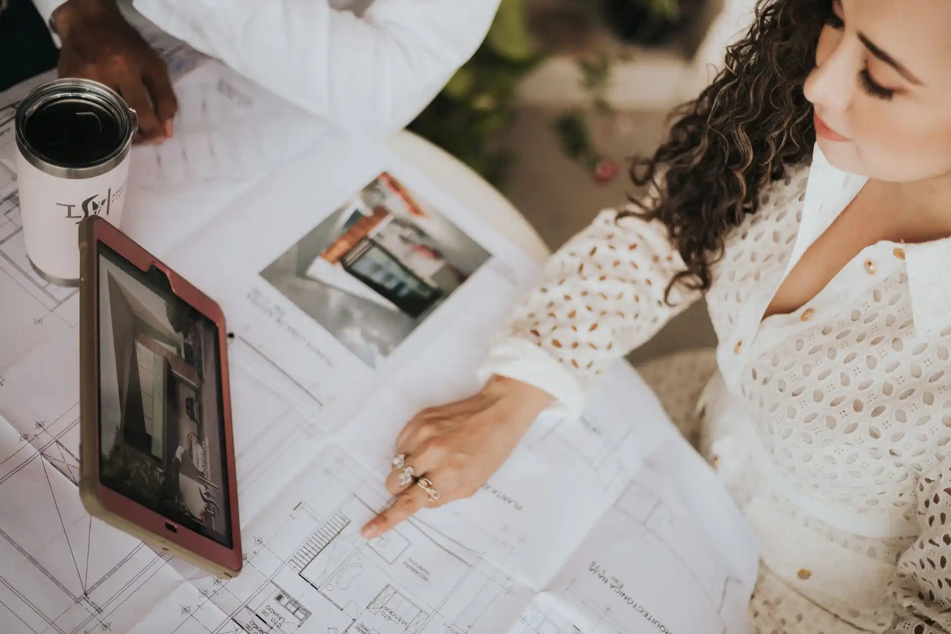 Seattle-area homeowners reviewing kitchen remodel plans with a contractor and designer at a table, sample materials, floor plans, and permit documents visible