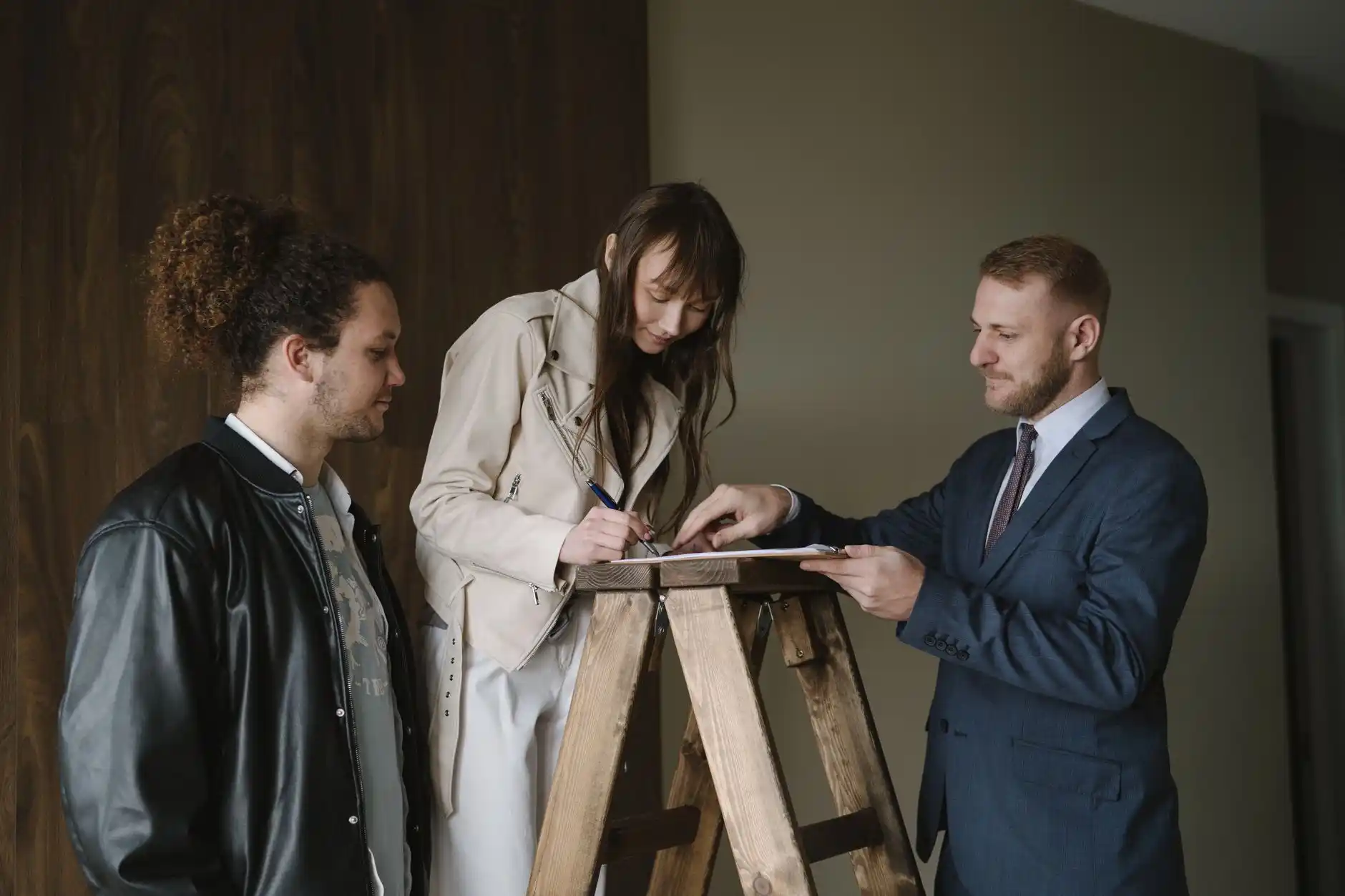 Homeowner and renovation contractor signing a detailed remodeling contract beside architectural plans, payment milestone checklist, and material samples