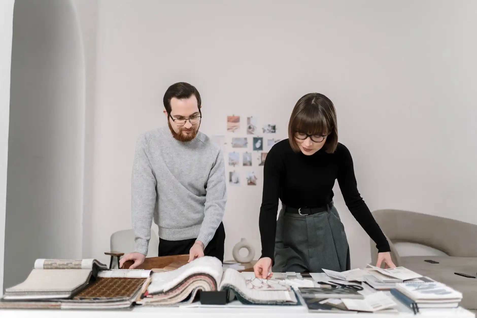 Photorealistic scene of a residential designer, construction project manager, and homeowners reviewing floor plans and material samples around a kitchen island in a partially re...