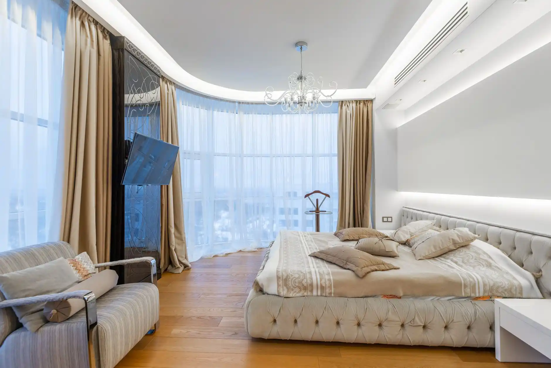 Bright staged Seattle primary bedroom with simple neutral bedding, two compact nightstands, one large artwork, uncluttered surfaces, warm wood accents, and soft overcast daylight