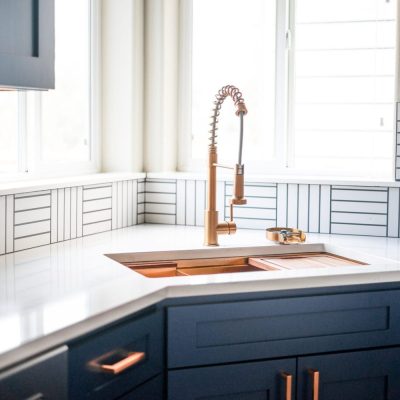 Navy kitchen with copper faucet and white countertops, United Signature remodel