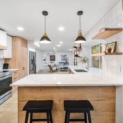 Light-wood kitchen island with brass pendants, United Signature remodel