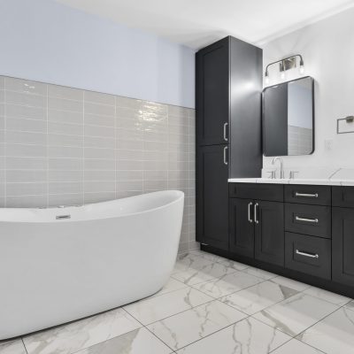 freestanding tub in tile bathroom with black cabinets