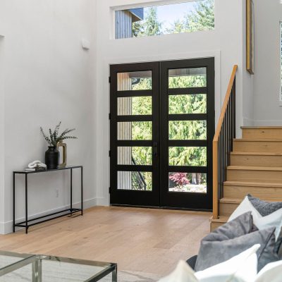 entry room staircase with black door and hardwood floors
